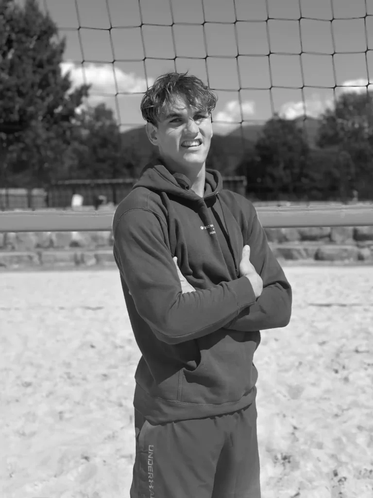 BSC Webdesign Athlete Tobias Wallner im schwarz-weißen Portrait mit Hoodie am Beachvolleyballfeld.