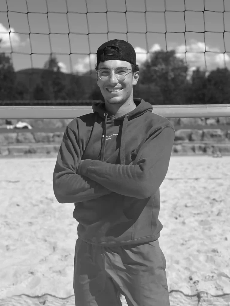 BSC Webdesign Athlete Valentin Stöllinger im schwarz-weißen Portrait mit Hoodie am Beachvolleyballfeld.