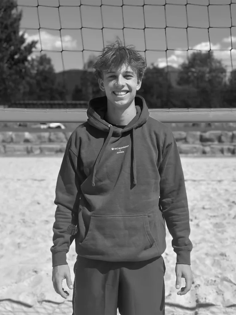 BSC Webdesign Athlete Wendelin Woertl im schwarz-weißen Portrait mit Hoodie am Beachvolleyballfeld.