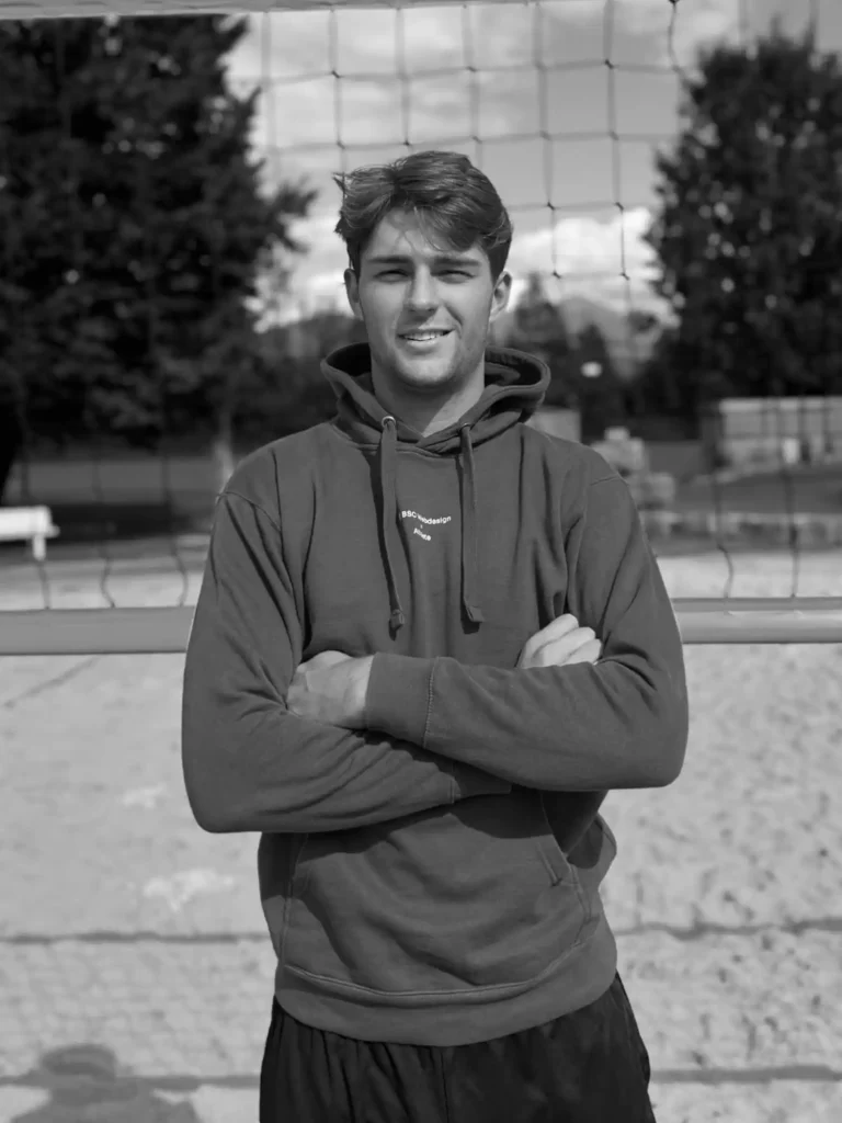 BSC Webdesign Athlete Xaver Stadlmann im schwarz-weißen Portrait mit Hoodie am Beachvolleyballfeld.